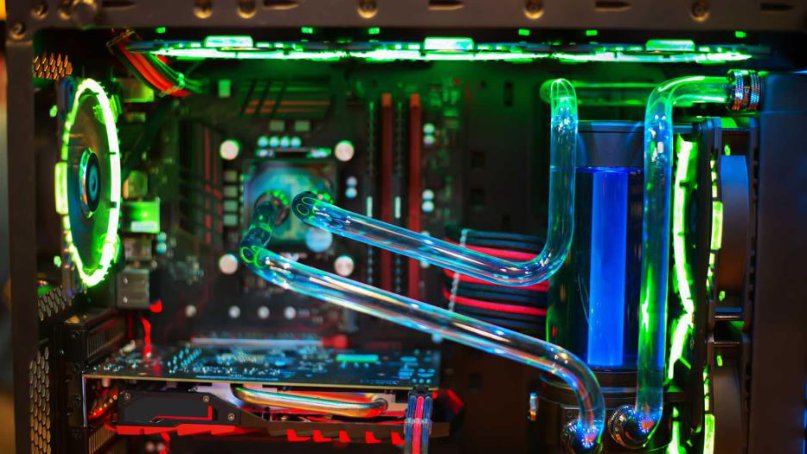 Close-up of a liquid-cooled computer with coolant tubing, radiators, and fans lit in green and red.
